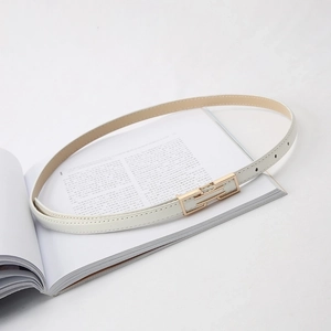 Detail of a thin white leather belt featuring a polished gold rectangular metal buckle