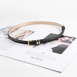 Cintura sottile in pelle nera da donna con fibbia a H dorata su una rivista trendy