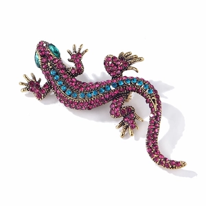 Vintage gold lizard brooch with blue and pink rhinestones on a white background