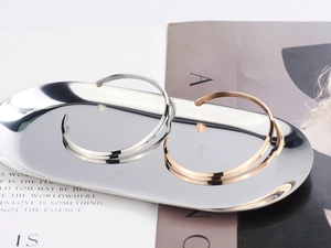 Minimalist C-shaped open bangles in rose gold and silver finishes on a tray