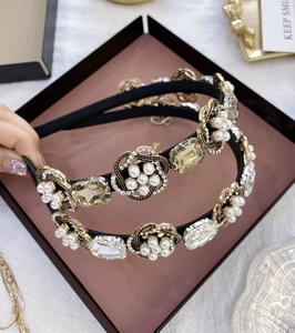 Détail d'un serre-tête baroque avec perles et cristaux posé sur un plateau rétro chic