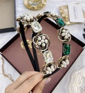 Détail d'un serre-tête baroque avec cristaux émeraude et ornements floraux en perles