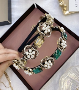 Détail d'un serre-tête baroque avec perles et strass émeraude sur monture en métal doré