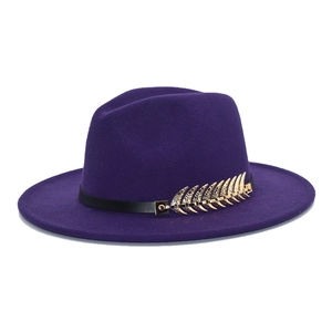 Detail of purple wool fedora hat featuring a black band and decorative golden leaf pin