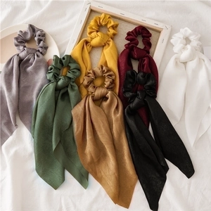 Satin bow hair scrunchies in seven colors with long ribbons on white fabric