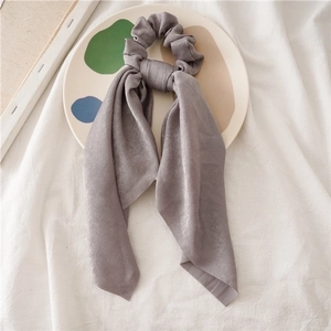 Detailed view of long grey satin scrunchie with streamers on artistic plate