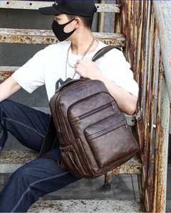 Detail of vintage dark brown PU leather backpack on street style male model outdoors