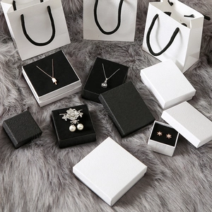 Minimalist black and white jewelry gift boxes and paper bags on grey velvet background