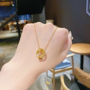 Elegant gold necklace with interlocking rings and pavé zircon pendant shown on hand