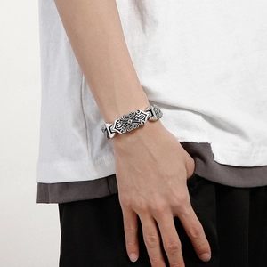Detail of vintage silver steel bracelet with cross and vine engravings on wrist