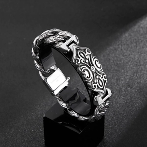 Macro detail of men's vintage stainless steel bracelet with relief totem and cuban chain
