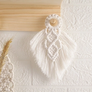 Handmade bohemian cotton macrame leaf wall hanging decor on a white brick background
