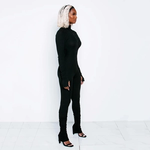 Detail showing side view of black bodycon jumpsuit with turtleneck and ruched leg cuffs