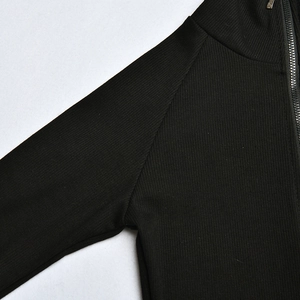Close-up of black ribbed knit bodysuit featuring a high collar and metal front zipper