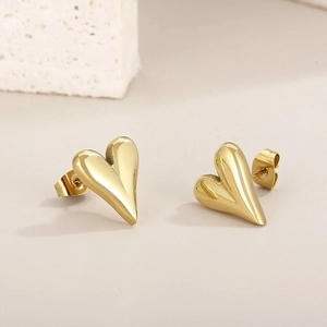 Close-up of heart-shaped gold studs on a textured stone over beige background
