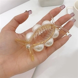 Detail of large hair claw clip with elegant white pearls and a gold-tone metallic finish