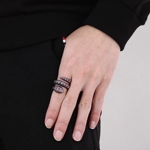 Detail of vintage silver snake ring with red accents wrapped around finger in punk style
