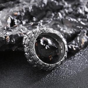 Macro shot of silver python ring with detailed snake scale texture on volcanic rock