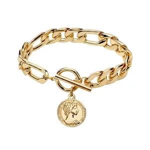 Detailed macro view of a vintage gold-toned Figaro chain bracelet with a round coin pendant