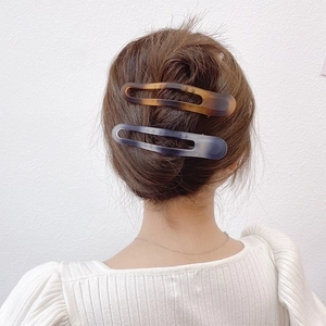 Close-up of tortoise shell and blue-grey gradient acrylic hair clips on a hairstyle