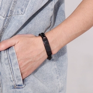 Close-up of a men's black stainless steel chain bracelet with a curved plate on wrist