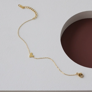 Macro shot of minimalist gold heart charm bracelet with adjustable extension chain