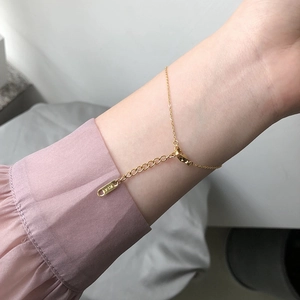 Close-up of gold chain bracelet with K14 engraved tag on a woman's wrist