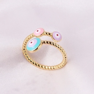 Macro shot of gold-plated evil eye ring with pink, purple, and blue enamel details