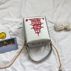 Macro detail of cube-shaped silver PU crossbody bag with red pagoda print and chain