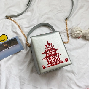 Close-up of silver square box bag with red pagoda print and gold chain strap detail