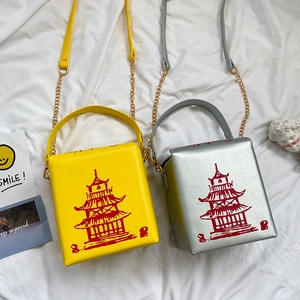 Detail of yellow and silver crossbody bags with red pagoda print and gold chain straps