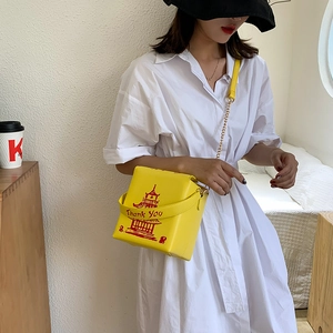 Detail of yellow takeout box shoulder bag with red pagoda print and chain strap