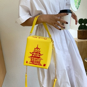Close-up of creative yellow Chinese takeout box crossbody bag with pagoda print
