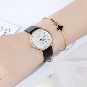 Detail shot of elegant quartz watch with leather strap and gold clover bracelet set