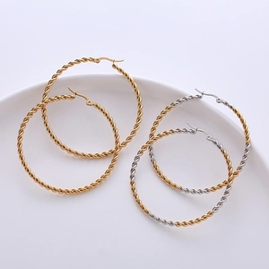 50mm twisted hoop earrings in gold and two-tone finishes on a minimalist tray