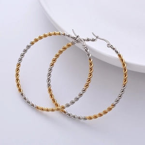 Close-up of 50mm twisted two-tone gold and silver hoop earrings in chunky rope style