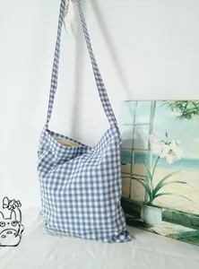 Detailed view of blue plaid cotton crossbody bag featuring wide canvas shoulder strap