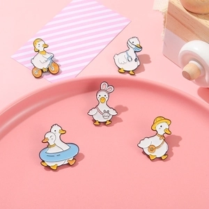 Five cute enamel duck brooches with cycling and doctor themes on pink background