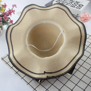 Elegant wide brim wavy straw hat in beige and black for sun protection and vacation