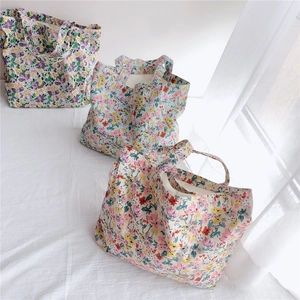 Detailed shot of three floral cotton tote bags with assorted patterns on a white fabric