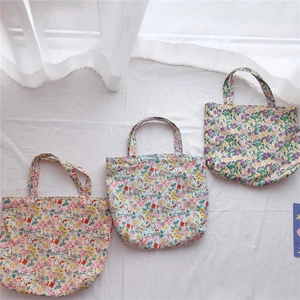 Three assorted floral cotton tote bags in red, pink and purple on white fabric background