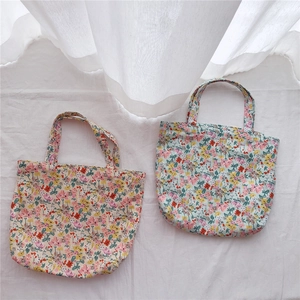 Detailed view of floral cotton tote bags in pink and blue on a soft white background