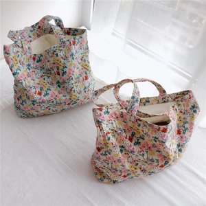 Detail of floral cotton tote bags in light blue and cream with soft natural lighting