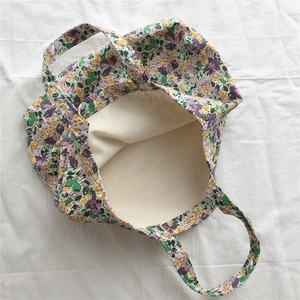 Detail of floral canvas tote bag with purple and yellow patterns and beige inner lining