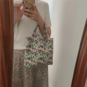 Detail of floral canvas handbag featuring purple and yellow blossoms with sturdy handles