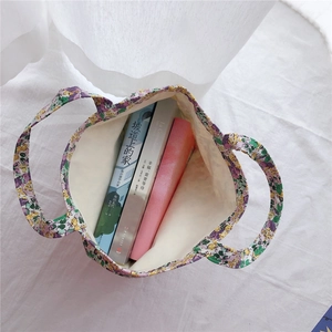 Detailed top view of a floral cotton tote bag showing capacity with three books inside