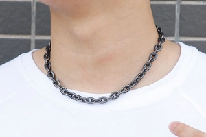 Primo piano di una collana a bilanciere in acciaio al titanio nero su un modello