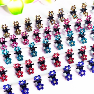 Détail de mini pinces à cheveux fleurs avec strass colorés sur présentoir blanc