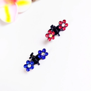 Détail de mini pinces à cheveux à fleurs ornées de strass rouges et bleus