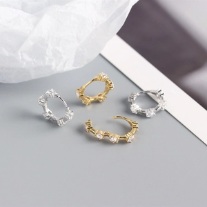 Close-up of gold and silver S925 sterling silver huggie earrings with round zircons